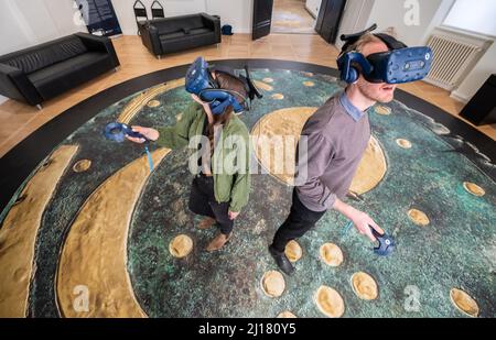 23 mars 2022, Saxe-Anhalt, Halle (Saale): Deux visiteurs regardent le Nebra Sky Disk sur des lunettes de réalité virtuelle au Musée d'État de la Préhistoire. L'exposition originale est actuellement en exposition à Londres. Avec l'aide des lunettes VR, les visiteurs peuvent profiter d'une animation artistique d'une durée d'environ dix minutes. Il emmène les visiteurs au Mittelberg près de Nebra, où le disque de ciel a été trouvé, et leur permet de glisser sur l'horizon sur un navire doré. Photo: Christian Modla/dpa Banque D'Images