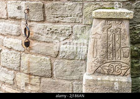 Une pierre de symbole Pictish au pied de la tour ronde Abernethy, une tour en pierre de 22 mètres de haut de style irlandais à Abernethy, Perth et Kinross, en Écosse au Royaume-Uni Banque D'Images