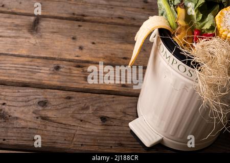 Vue en grand angle des déchets organiques dans le bac à compost blanc sur une table en bois Banque D'Images