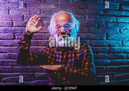Homme asiatique senior dansant et jouant avec des lunettes futuristes de réalité augmentée - Metaverse innovation nouveau concept de tendance - Focus sur la main gauche Banque D'Images