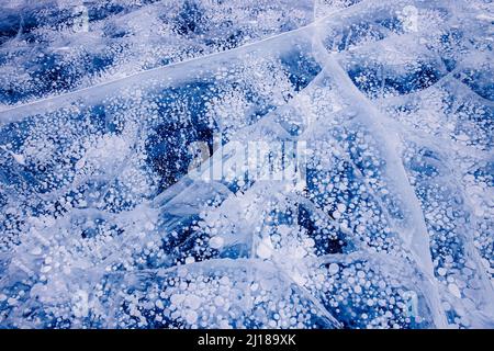 Bulles de méthane de gaz congelées dans la glace d'hiver du lac Baikal, arrière-plan abstrait. Banque D'Images