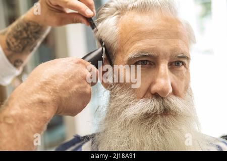 Coiffeur faisant une coupe de cheveux élégante pour un vieil homme beau Banque D'Images