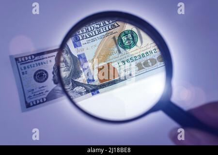 Concept sur le thème de la vérification de l'authenticité de l'argent. Poignée tenant la loupe pour l'inspection du dollar Banque D'Images