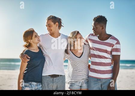 Pouvons-nous faire chaque jour un jour de plage. Photo d'un groupe de jeunes amis heureux posant sur la plage ensemble. Banque D'Images