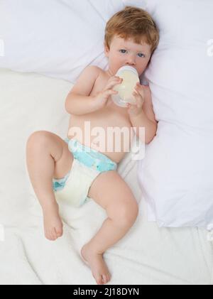 Détente avec ma formule. Prise de vue en longueur d'un bébé allongé en buvant une bouteille de lait maternisé. Banque D'Images