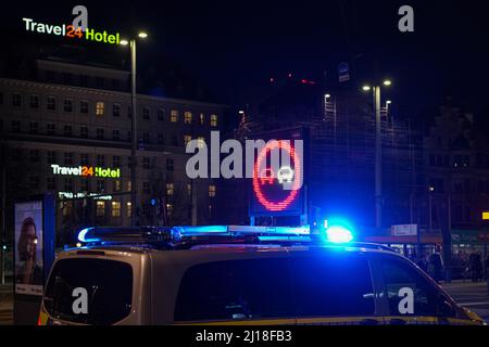 Un véhicule de police arrête la circulation la nuit avec des feux bleus et un panneau d'avertissement au néon rouge et blanc. Banque D'Images