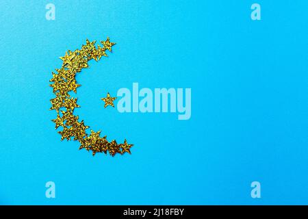 Forme de lune des paillettes luminescentes. Arrière-plan bleu, espace de copie et vue de dessus. Banque D'Images