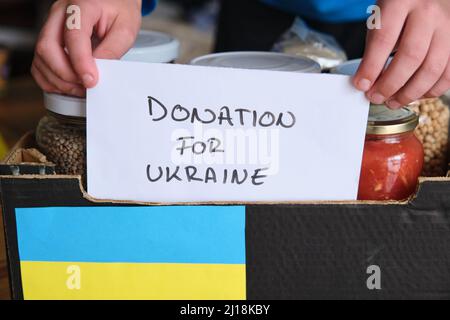 Une personne qui place un panneau sur une boîte contenant de la nourriture à donner aux réfugiés en Ukraine. Banque D'Images