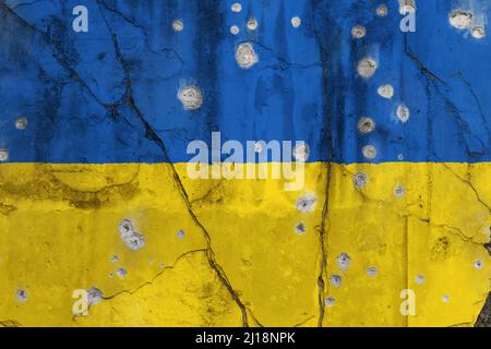 Photo plein cadre d'un drapeau de l'Ukraine abîmé peint sur un mur fissuré avec des trous de balle. La violence et la guerre en Ukraine concept. Banque D'Images