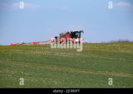 Un pulvérisateur de récolte rouge travaillant dans un champ à Warwickshire, en Angleterre, lors d'une journée ensoleillée de printemps. Banque D'Images