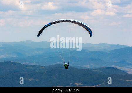 parapente au-dessus de la vallée de la montagne. sports extrêmes en plein air. aventure et concept de voyage. nuages sur le ciel en été Banque D'Images