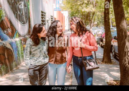 Trois jeunes femmes descendent dans la rue, elles sourient, jouent et ont un bon moment. Banque D'Images