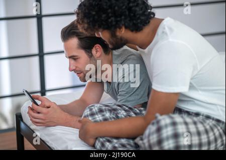 Couple gay biracial regardant l'écran du smartphone Banque D'Images