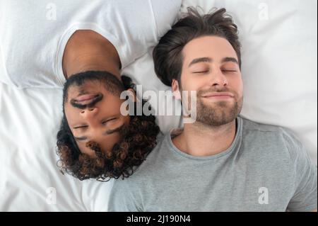 Jeune couple biracial gay dormant au lit Banque D'Images