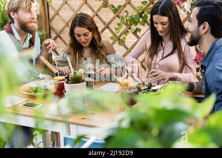 Les jeunes mangent un brunch et boivent des smoothies au bar-restaurant sain - attention au visage de la fille droite Banque D'Images