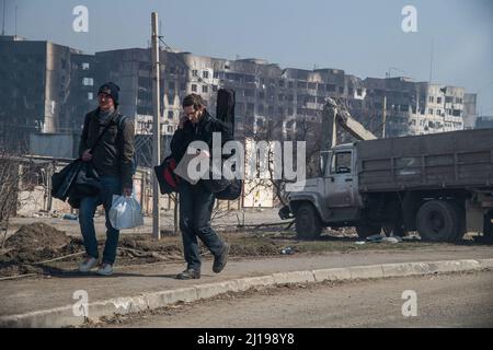 Marioupol, Ukraine. 23rd mars 2022. Avec un panneau en carton portant la mention 'Volodarsk', deux jeunes hommes tentent de faire une randonnée depuis les ruines de Marioupol jusqu'en Russie. La bataille entre les forces russes et pro-russes et les forces ukrainiennes en déférence, sous la direction du bataillon Azov, se poursuit dans la ville portuaire de Marioupol. (Photo de Maximilian Clarke/SOPA Images/Sipa USA) crédit: SIPA USA/Alay Live News Banque D'Images