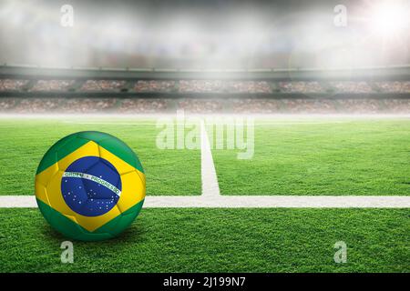 Football dans un stade en plein air lumineux avec drapeau peint du Brésil. Concentrez-vous sur le premier plan et le ballon de football avec une faible profondeur de champ sur l'arrière-plan et Banque D'Images