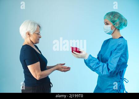 Importance métaphorique de la santé. Cardiologue donnant un cœur artificiel à une grand-mère caucasienne âgée atteinte d'une maladie cardiovasculaire. Photo de haute qualité Banque D'Images