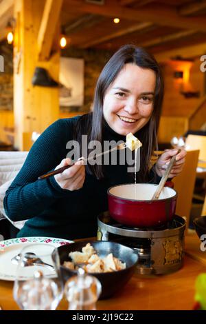 Femme ayant repas dans un restaurant suisse, en train de manger de la fondue Banque D'Images