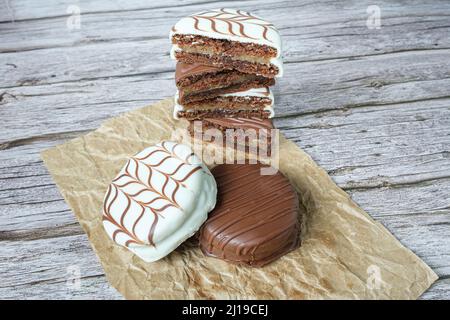 Gâteaux traditionnels au miel brésilien avec glaçage au chocolat blanc. Bourré de dulce de leche. En arrière-plan, plusieurs coupées en deux et empilées. Banque D'Images