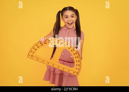 surprise enfant tenir l'école outil mathématique protracteur règle sur fond jaune, école Banque D'Images