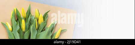 Bannière horizontale avec tulipes jaunes sur béton gris avec espace de copie. Arrière-plan pour la fête des femmes, le 8 mars jour de la Saint-Valentin, le 14 février. Pose à plat Banque D'Images