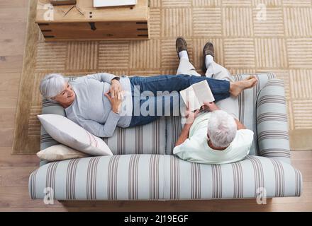 La poésie est le langage de l'amour Un homme âgé lisant à sa femme comme elle se trouve sur le canapé. Banque D'Images