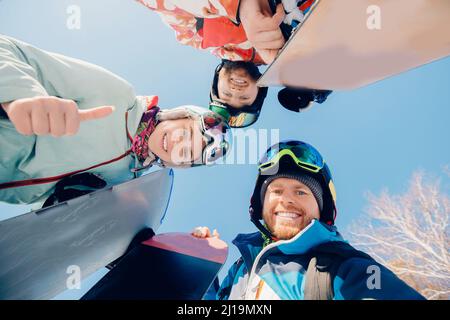 Équipe d'amis homme et femme ski et snowboard faire selfie photo en hiver avec lumière du soleil sur la station de ski. Banque D'Images