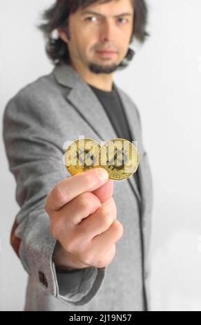 Homme d'affaires portant un costume, tenant Bitcoin BTC crypto monnaie pièces d'or, nouveau concept de monnaie virtuelle. Technologie minière ou blockchain Banque D'Images