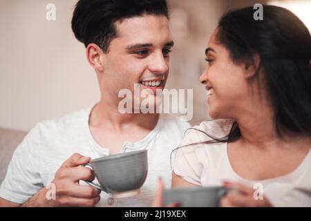 Le parfait début de journée. Petit cliché d'un jeune couple affectueux qui déguste son café du matin sur le canapé du salon. Banque D'Images