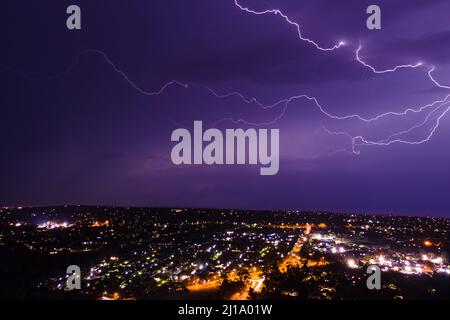 Éclair éclair se déchargeant dans les nuages orageux au-dessus des lumières de rue photographie aérienne de nuit Banque D'Images