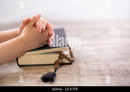 Les mains de l'enfant ont classé dans la prière sur la bible, Nouveau Testament. Prière et Dieu merci.religion chrétienne contexte concept. Banque D'Images