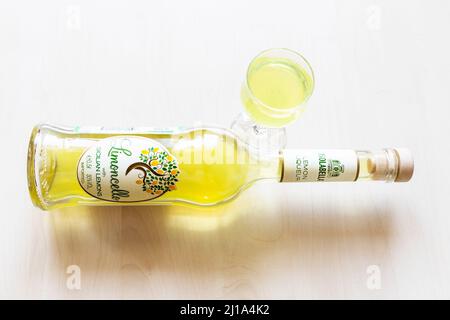 Moscou, Russie - 20 mars 2022 : verre de liqueur et bouteille couchée de limoncello isolabella sicilienne sur table pâle. Le limoncello est de la liqueur de citron italienne M. Banque D'Images