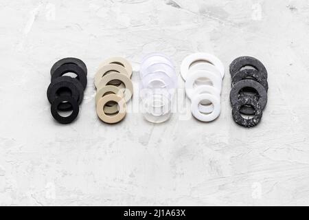 beaucoup de différents joints pour la plomberie des systèmes d'eau sur fond de béton gris (caoutchouc, caoutchouc sous vide, silicone, ptfe, paronite) Banque D'Images