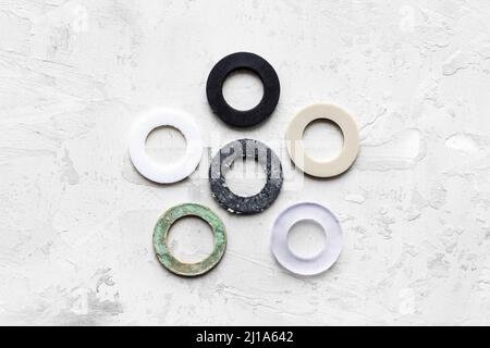vue de dessus des différents joints pour la tuyauterie des systèmes d'eau sur fond en béton gris (caoutchouc, caoutchouc sous vide, silicone, ptfe, paronite) Banque D'Images