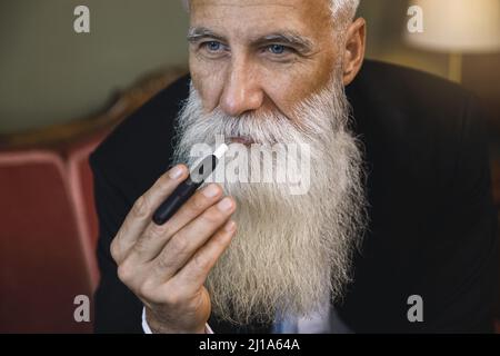 Beau homme âgé fumant système de chauffage du tabac Banque D'Images