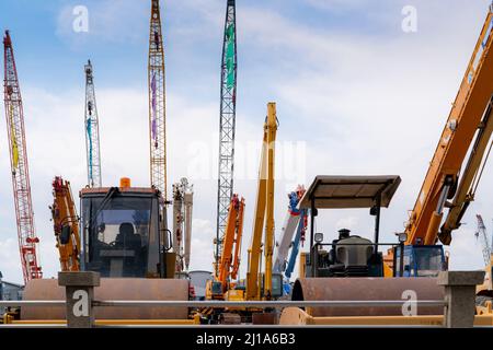 Rouleau de route, grue mobile et pelle rétro avec flèche longue. Machines lourdes garées dans la cour de vente aux enchères de machines d'occasion. Rouleau de route, grue mobile. Banque D'Images