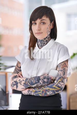 Des shes prêts à faire du rock sur la scène de l'entreprise. Une jeune femme d'affaires couverte de tatouage dans son bureau. Banque D'Images