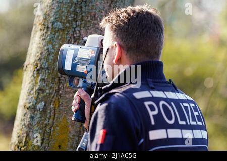 Mannheim, Allemagne. 24th mars 2022. Un agent de police vérifie la vitesse des véhicules à l'aide d'un dispositif laser sur l'autoroute fédérale 36. Plusieurs États allemands participent au marathon européen de 24 heures avec appareil photo. Cela implique que la police utilise un nombre accru de véhicules pour surveiller les infractions à la vitesse sur les routes. Credit: Uwe Anspach/dpa/Alamy Live News Banque D'Images