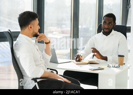 Un homme noir interviewe un nouvel employé dans le bureau de l'entreprise Banque D'Images