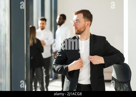 Portrait d'un travailleur de bureau homme confiant en lunettes et veste noire Banque D'Images