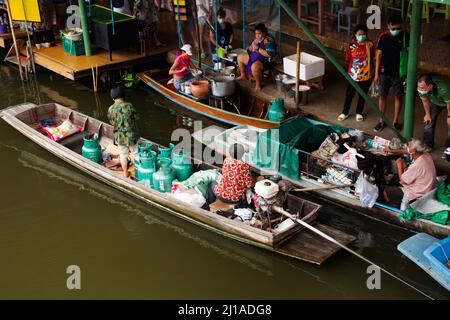 Les vieilles femmes thaïlandaises pagayer et faire de l'équitation bateaux en bois transportant et livrer le produit de réservoir de gaz à la boutique marchande dans le canal local Wat Takhian Floating Banque D'Images