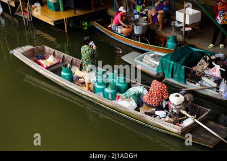 Les vieilles femmes thaïlandaises pagayer et faire de l'équitation bateaux en bois transportant et livrer le produit de réservoir de gaz à la boutique marchande dans le canal local Wat Takhian Floating Banque D'Images