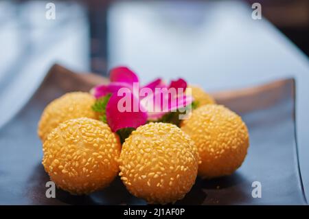 Boulettes de sésame frites croustillantes comme dessert sur une assiette noire Banque D'Images