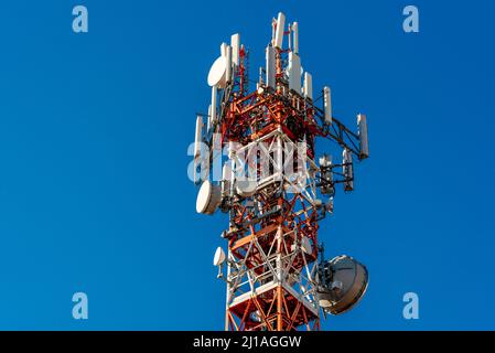 Tour en métal avec antennes de télécommunication et paraboles de couleur rouge et blanc sur bleu ciel, concept de réseau 5G haut débit, espace de copie Banque D'Images