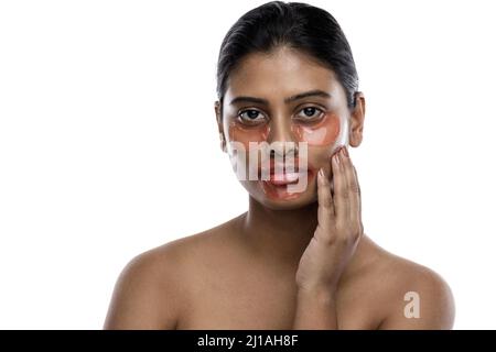 Belle femme indienne avec des timbres hydratants pour les yeux et un masque de lèvre sur son visage Banque D'Images