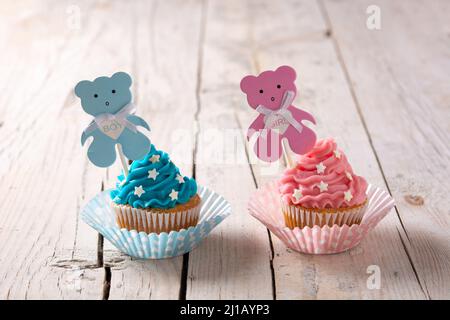 Petits gâteaux bleus et roses pour la douche de bébé sur une table en bois Banque D'Images