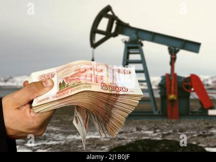 L'ombre de la plate-forme pétrolière contre le fond de l'argent russe. Concept de la vente de minéraux pour les roubles russes. Gagnez de l'argent grâce au gaz et au pétrole miniers Banque D'Images