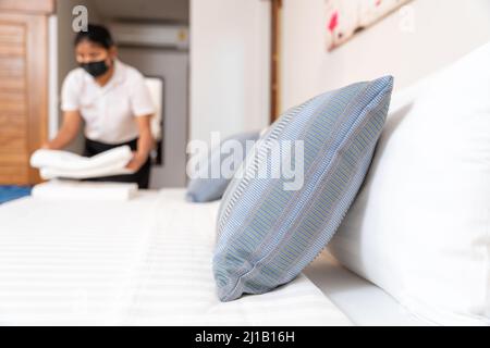 choisissez un oreiller focus, une femme de ménage mettant une pile de serviettes propres dans la chambre. Banque D'Images