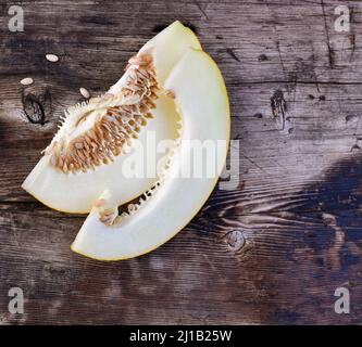 Tranches de melon mûr avec graines à l'intérieur sur une surface en bois. Banque D'Images